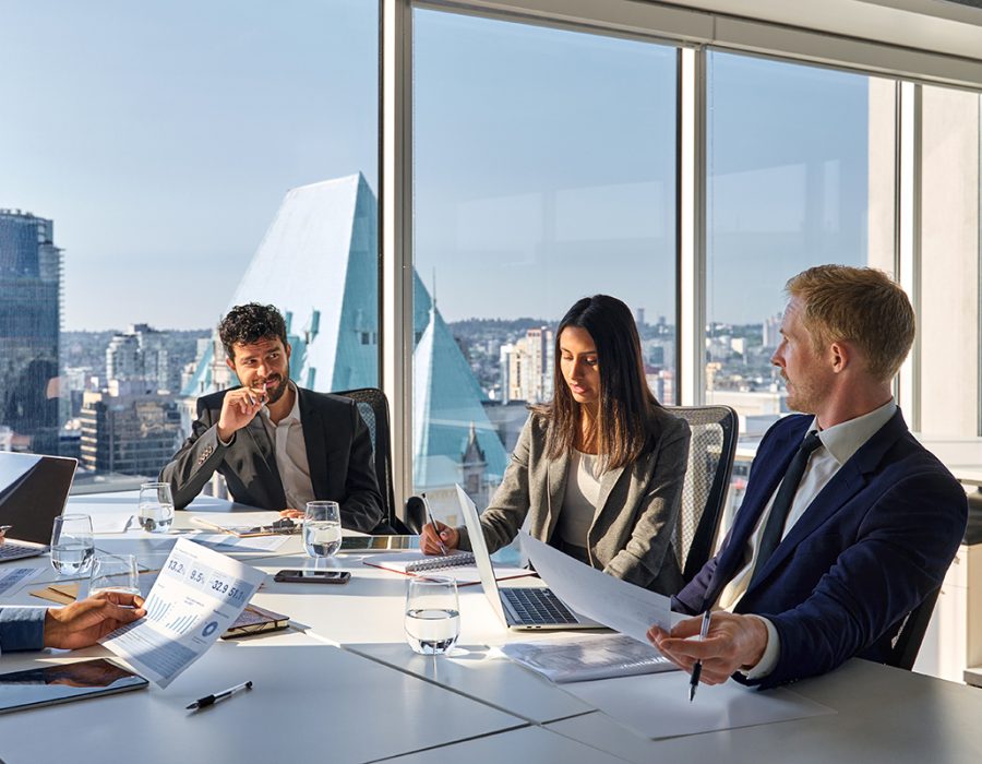 Busy international executives young team people working at board room table. Busy international executives young team people working at board room table. Diverse professional employees group discussing marketing project strategy working together in office meeting room.